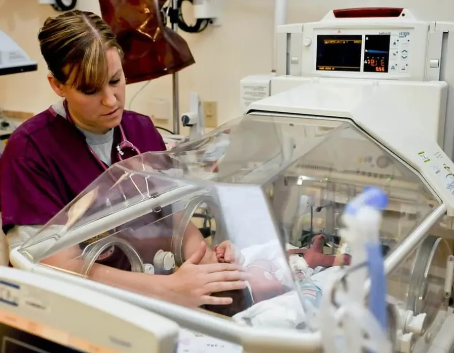 Neonatal nurse comforting infant in NICU